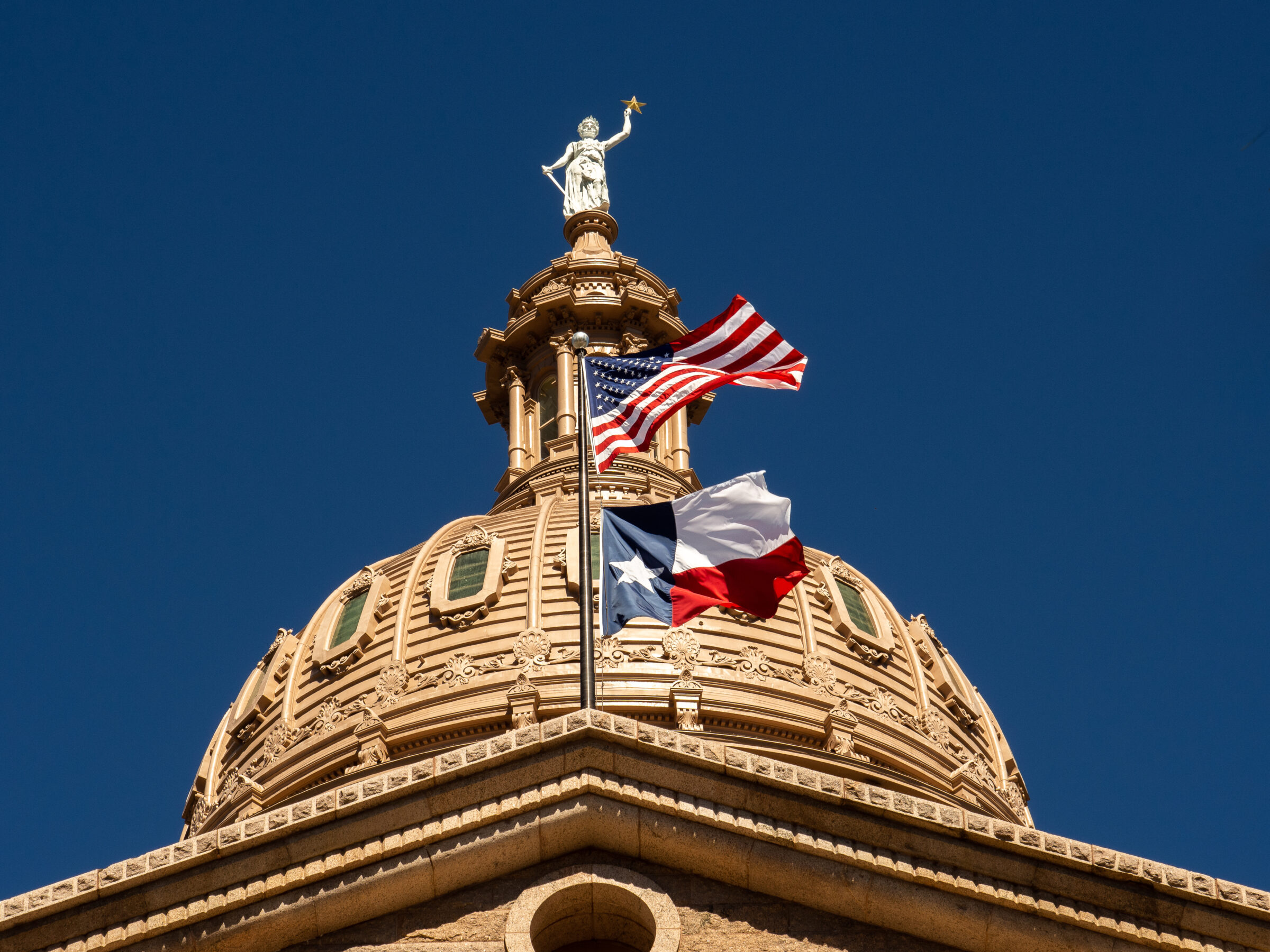 US flag and flag of Texas flying proudly above the Texas State Capital