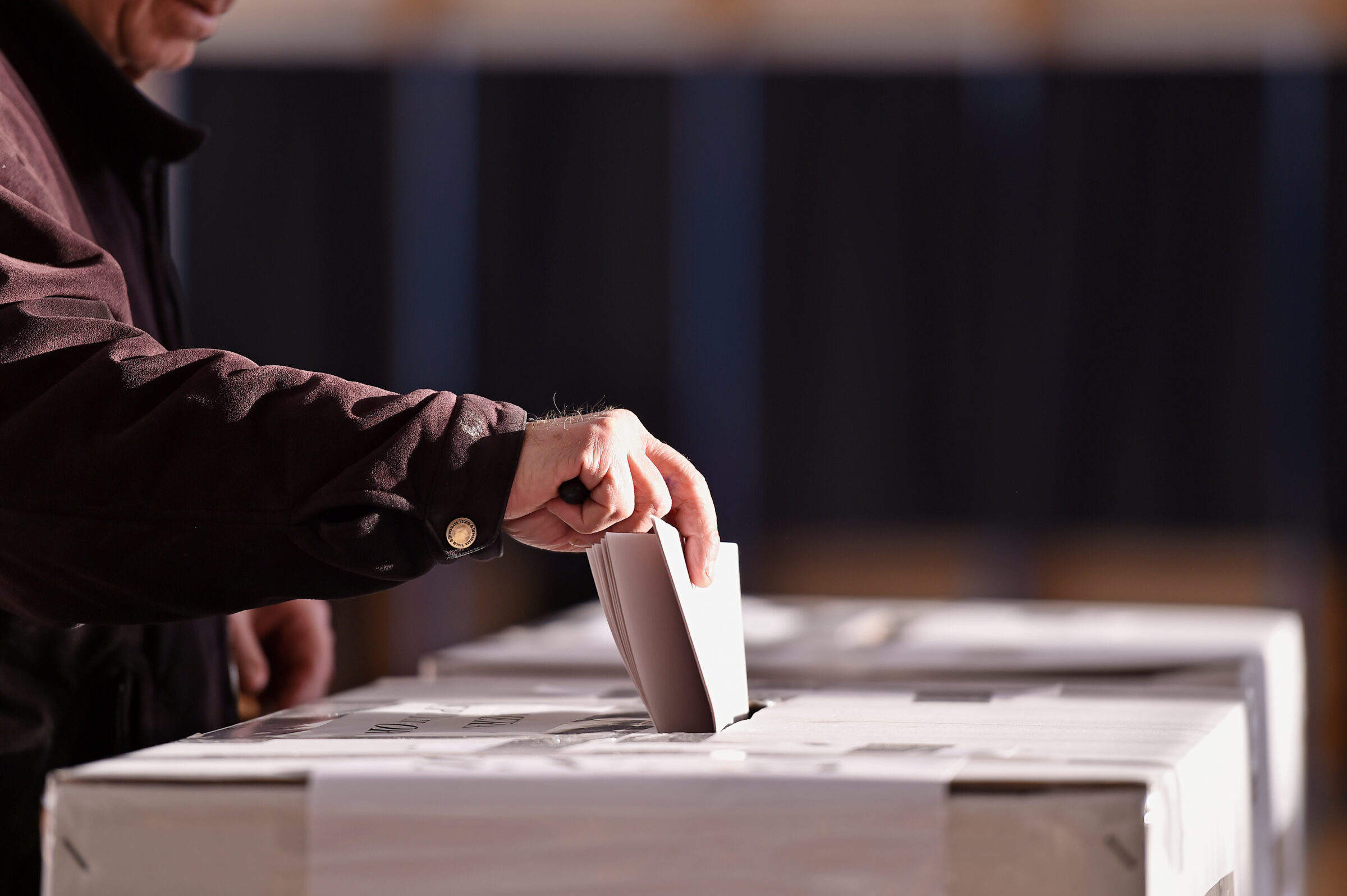 Person casting vote into ballot box